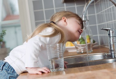 Niña bebiendo agua del grifo